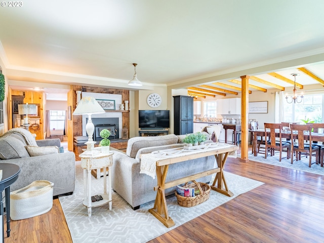 living room with a chandelier, light hardwood / wood-style flooring, and beam ceiling