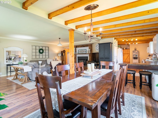 dining area featuring sink, ornamental molding, dark hardwood / wood-style flooring, a chandelier, and beamed ceiling