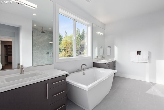 bathroom featuring plenty of natural light, double vanity, tile floors, and plus walk in shower