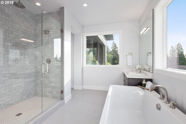 bathroom featuring tile flooring, a healthy amount of sunlight, independent shower and bath, and vanity with extensive cabinet space