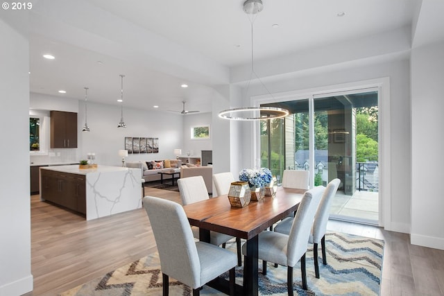 dining space featuring ceiling fan with notable chandelier and light wood-type flooring