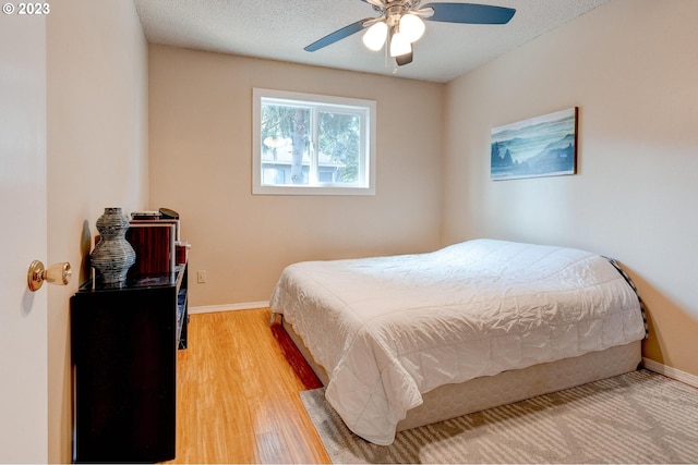 bedroom featuring ceiling fan, light hardwood / wood-style floors, and a textured ceiling