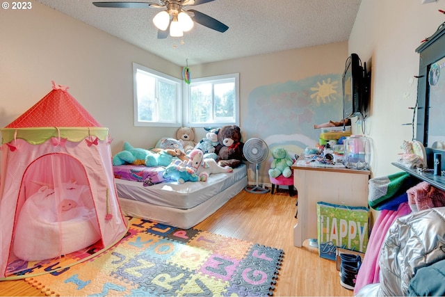 bedroom with ceiling fan, light wood-type flooring, and a textured ceiling