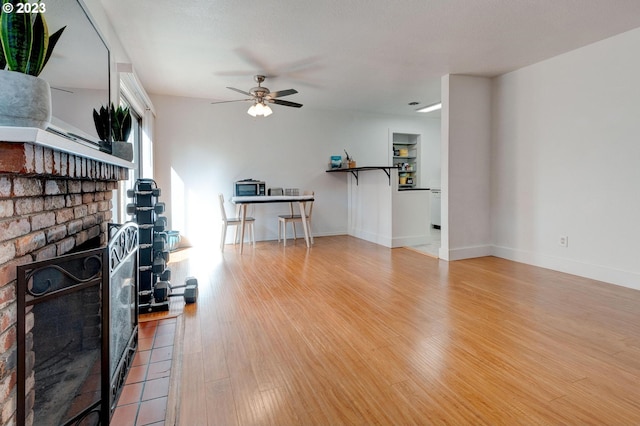 unfurnished living room featuring light hardwood / wood-style floors, ceiling fan, and a fireplace