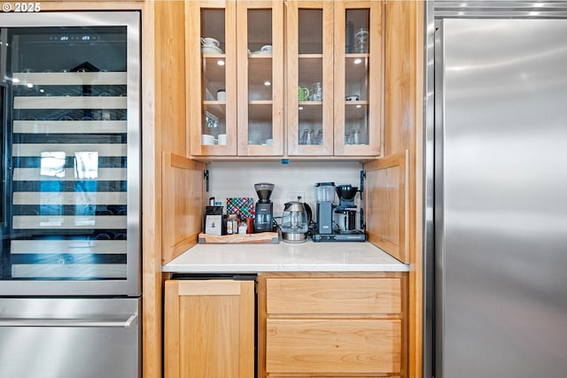 bar with stainless steel fridge, light brown cabinets, and beverage cooler