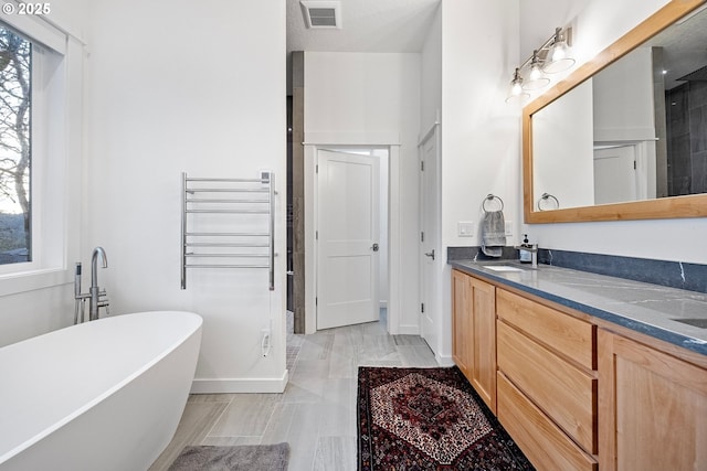 full bathroom featuring a soaking tub, double vanity, and baseboards