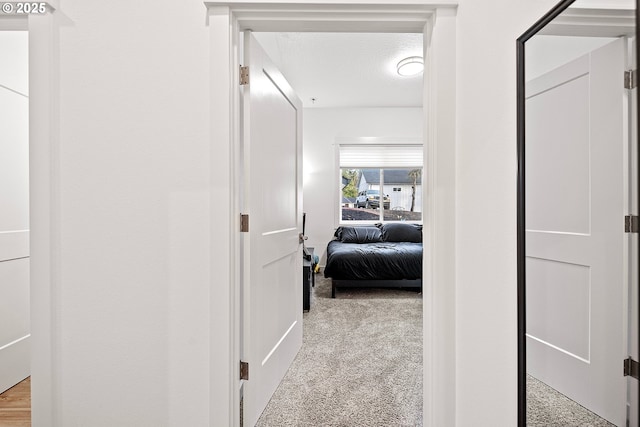 hallway featuring a textured ceiling and light colored carpet