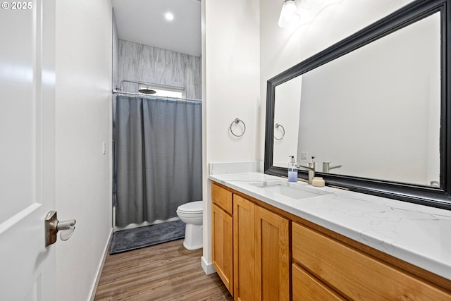 bathroom with walk in shower, hardwood / wood-style floors, vanity, and toilet