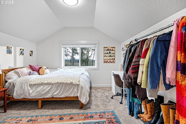 bedroom with carpet, lofted ceiling, a textured ceiling, and baseboards