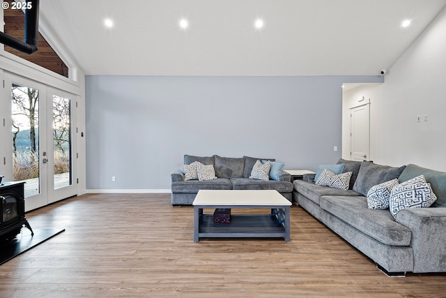 living area featuring french doors, a wood stove, light wood-style floors, high vaulted ceiling, and recessed lighting