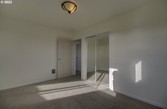 unfurnished bedroom with light carpet and a closet