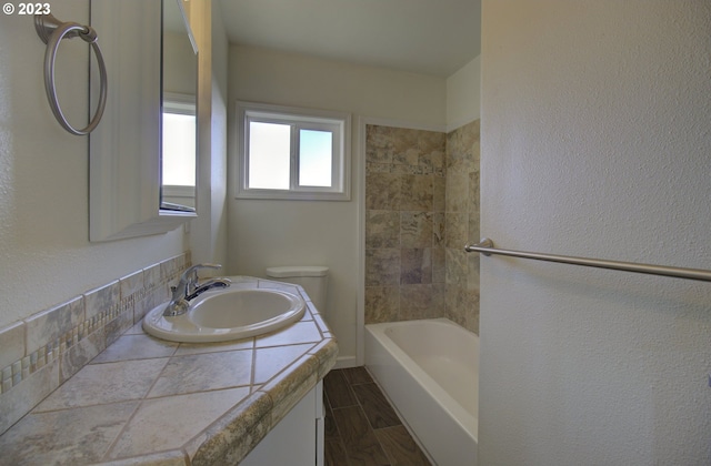 full bathroom featuring tiled shower / bath combo, toilet, and vanity