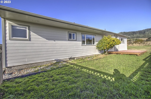 back of property featuring a deck and a lawn