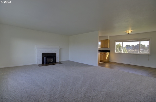 unfurnished living room with dark carpet and a brick fireplace