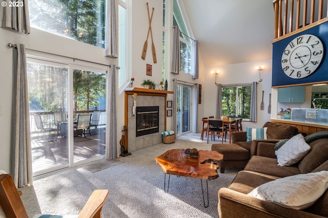 carpeted living room with a tiled fireplace, a towering ceiling, and a wealth of natural light