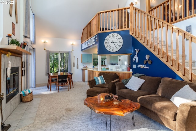 carpeted living room featuring a tiled fireplace and a towering ceiling