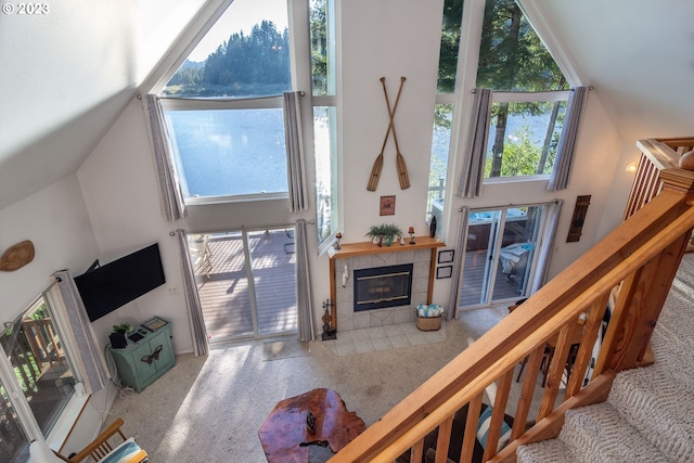 living room with light colored carpet, a tile fireplace, and a high ceiling