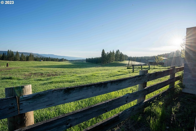 view of gate with a rural view and a lawn