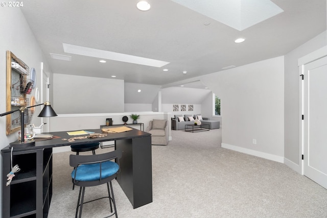 carpeted office featuring lofted ceiling with skylight