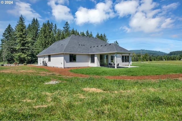 rear view of property with a mountain view, a lawn, and a patio