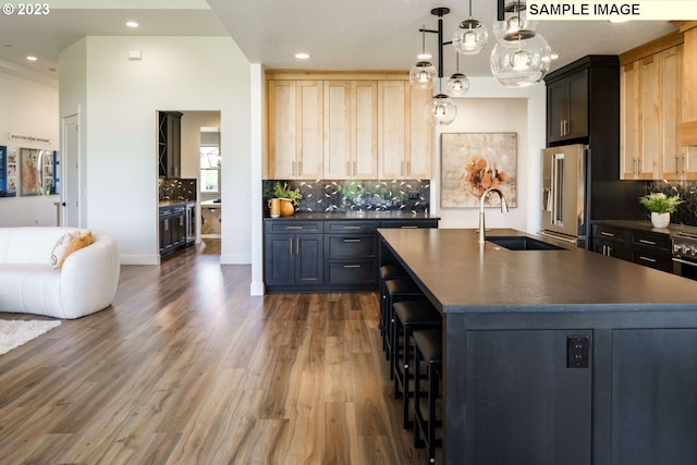 kitchen featuring light brown cabinets, sink, dark wood-type flooring, high end fridge, and a kitchen island with sink