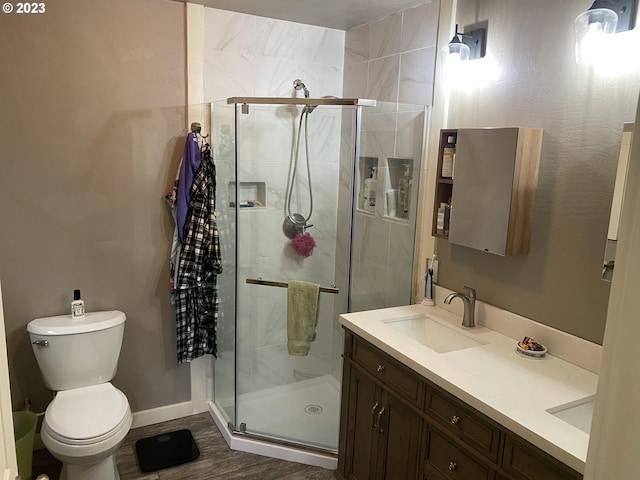 bathroom with wood-type flooring, toilet, an enclosed shower, and vanity with extensive cabinet space