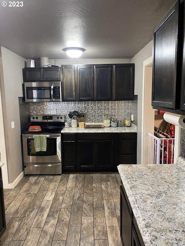 kitchen with dark hardwood / wood-style flooring, light stone countertops, stainless steel appliances, and tasteful backsplash