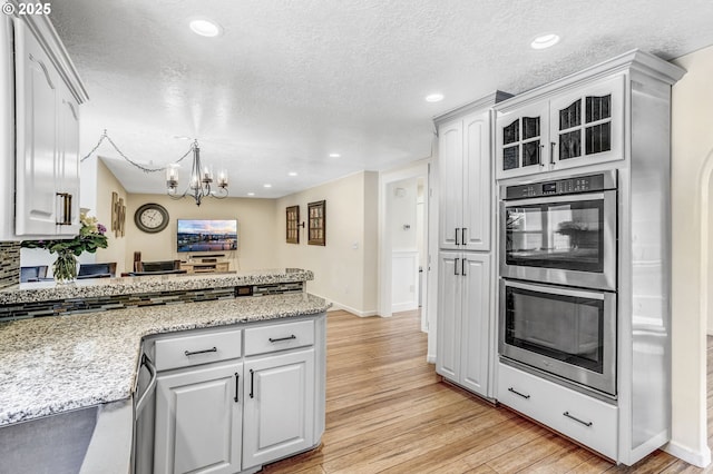 2940 Robinwood Dr, Forest Grove, OR 97116 - kitchen with double oven, a peninsula, light wood-type flooring, a chandelier, and a textured ceiling