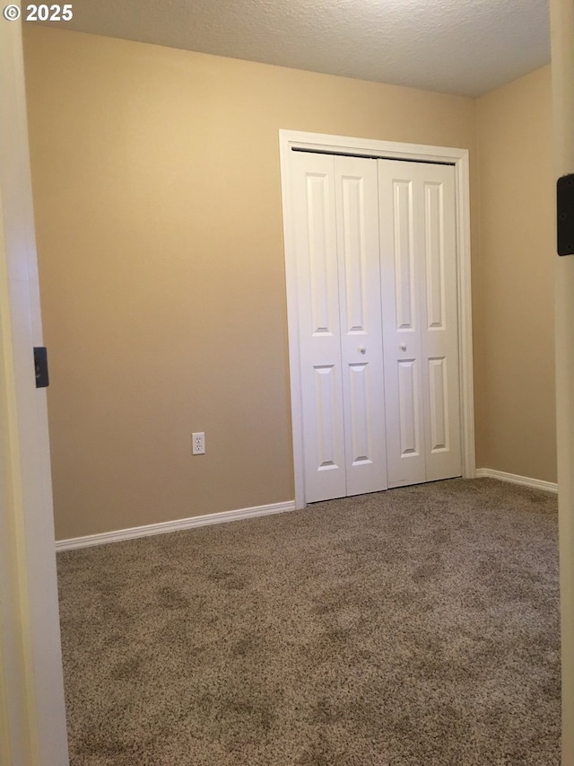 unfurnished bedroom featuring carpet, a textured ceiling, and a closet