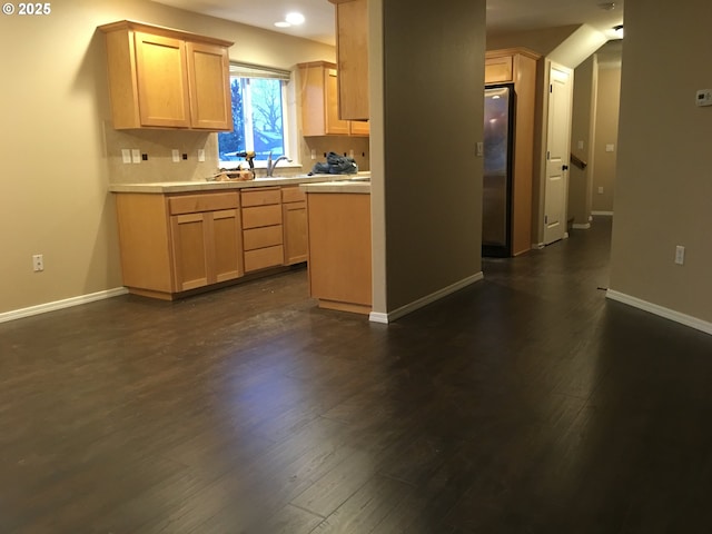 kitchen with light brown cabinetry, dark hardwood / wood-style flooring, and stainless steel refrigerator