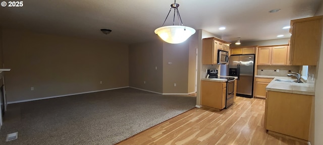 kitchen featuring light brown cabinetry, sink, hanging light fixtures, light hardwood / wood-style flooring, and stainless steel appliances