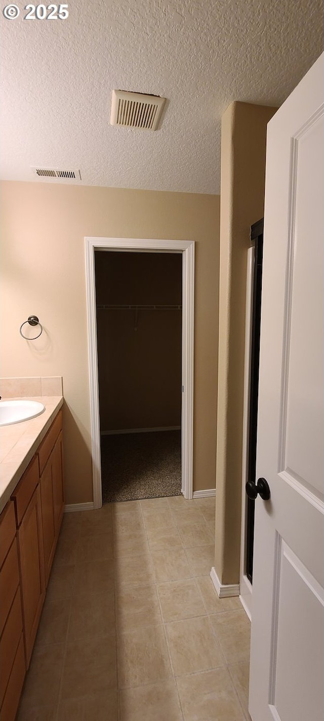 bathroom featuring vanity, tile patterned flooring, and a textured ceiling