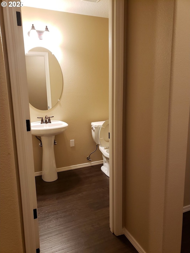 bathroom featuring hardwood / wood-style flooring, toilet, and sink