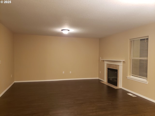 unfurnished living room featuring dark wood-type flooring, a fireplace, and a textured ceiling