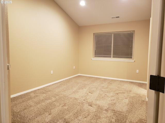 carpeted spare room featuring vaulted ceiling