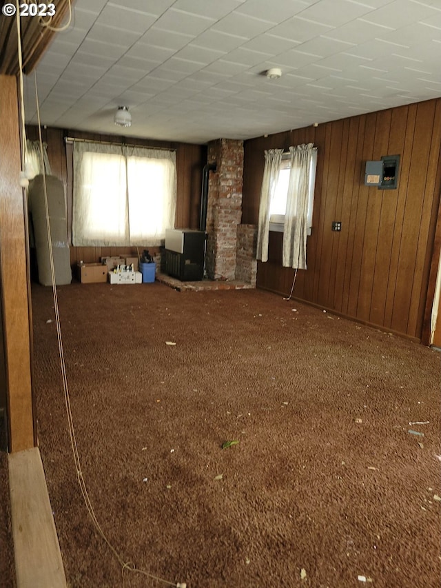 unfurnished living room featuring dark carpet, a healthy amount of sunlight, and a wood stove