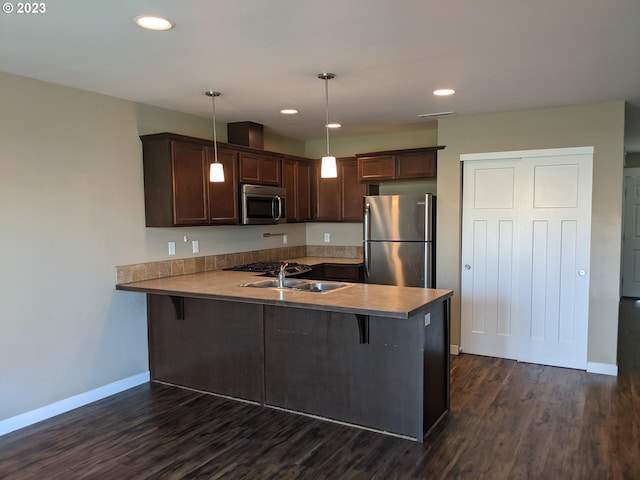 kitchen with kitchen peninsula, hanging light fixtures, dark hardwood / wood-style flooring, a breakfast bar area, and stainless steel appliances