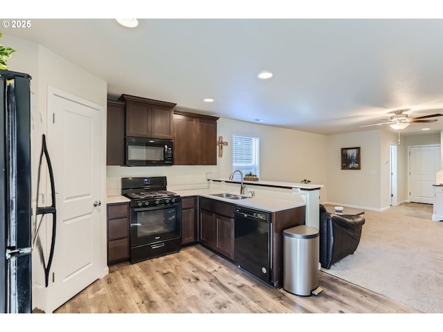 kitchen with a sink, a peninsula, black appliances, and dark brown cabinets