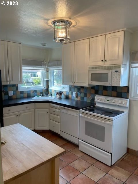 kitchen with white appliances, white cabinetry, tasteful backsplash, and decorative light fixtures