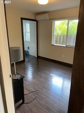 empty room featuring dark hardwood / wood-style floors and a wall mounted air conditioner