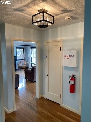 hall with a textured ceiling and dark hardwood / wood-style floors