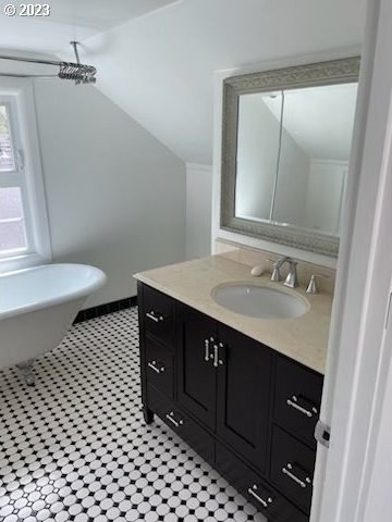 bathroom with vaulted ceiling, tile floors, and vanity