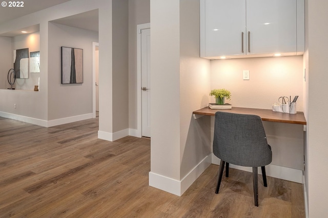 office featuring built in desk and hardwood / wood-style flooring