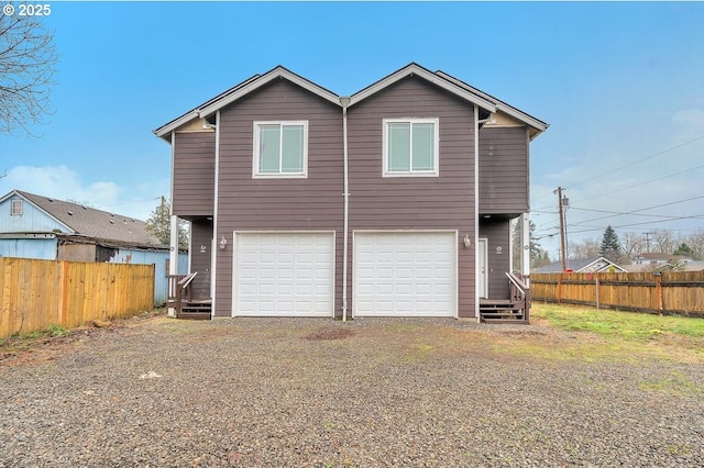 exterior space with an attached garage, gravel driveway, and fence