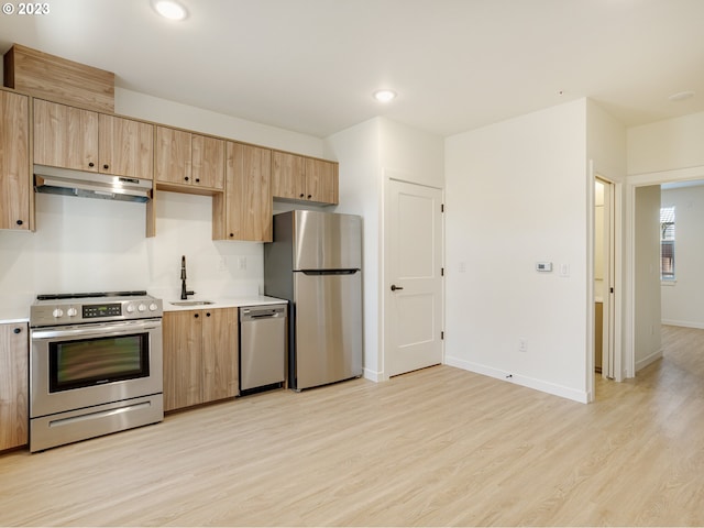 kitchen with appliances with stainless steel finishes, light brown cabinetry, light hardwood / wood-style floors, and sink