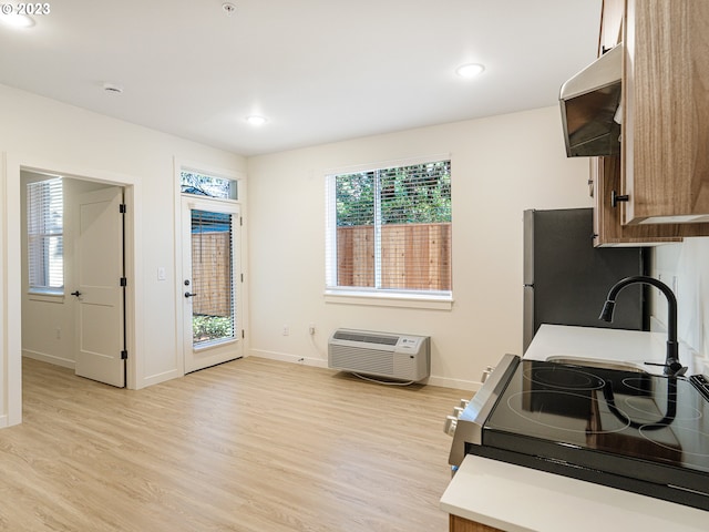 kitchen featuring stainless steel fridge, stove, extractor fan, and light hardwood / wood-style flooring