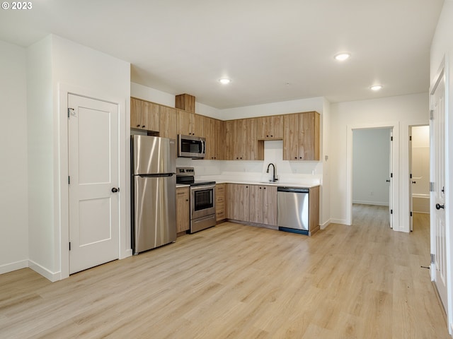 kitchen with appliances with stainless steel finishes, light hardwood / wood-style floors, and sink