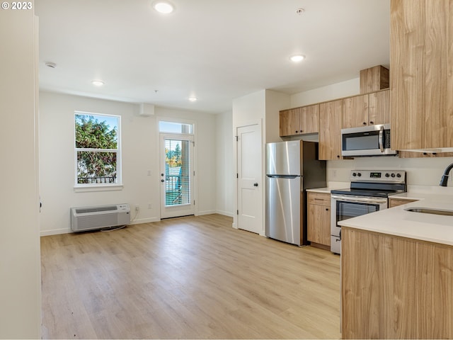 kitchen featuring light brown cabinetry, sink, an AC wall unit, appliances with stainless steel finishes, and light wood-type flooring