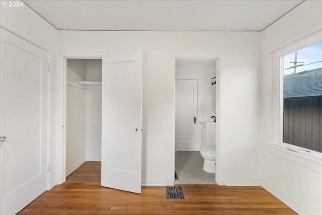 unfurnished bedroom with hardwood / wood-style flooring, a closet, and ensuite bath