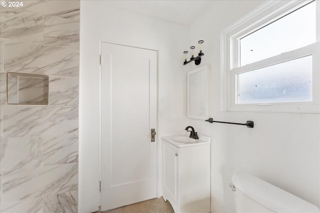 bathroom with a tile shower, vanity, and toilet